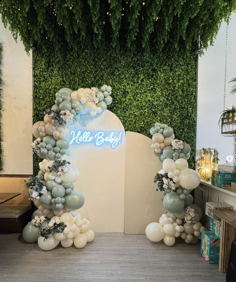 Sage and cream balloon installation with a glowing Hello Baby sign